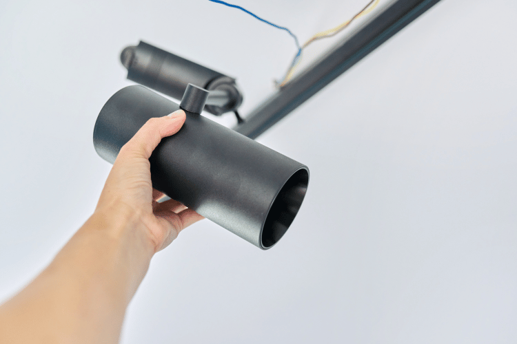 Close-up of a man installing black ceiling-mounted spotlights